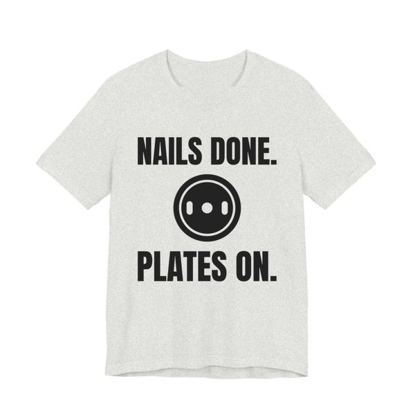 Ash t-shirt printed in dark ink with a weight plate between the words "Nails Done." and "Plates On."