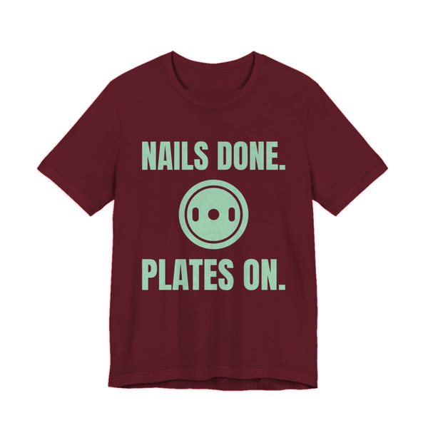 Maroon t-shirt printed in mint green ink with a weight plate between the words "Nails Done." and "Plates On."