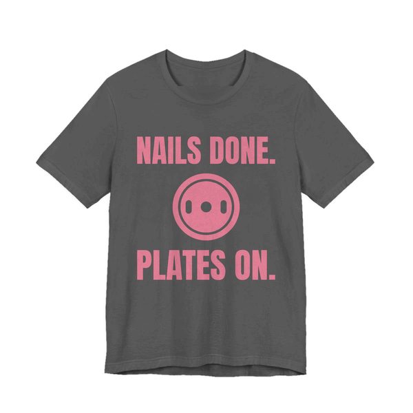 Asphalt t-shirt printed in rose pink ink with a weight plate between the words "Nails Done." and "Plates On."