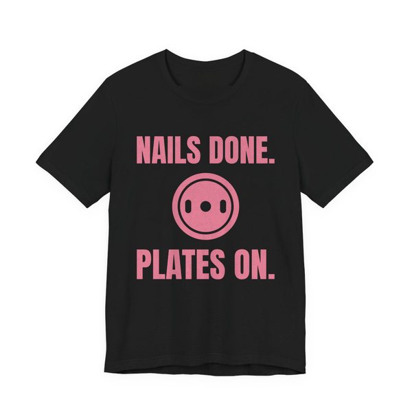 Black t-shirt printed in rose pink ink with a weight plate between the words "Nails Done." and "Plates On."