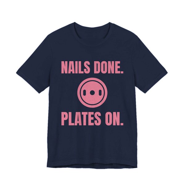 Navy t-shirt printed in rose pink ink with a weight plate between the words "Nails Done." and "Plates On."