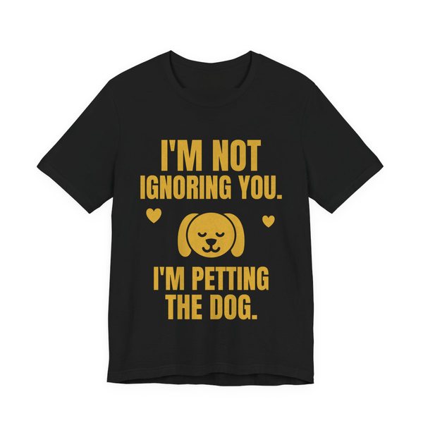 Black t-shirt printed in gold ink with a content dog face with hearts and the words “I'm Not Ignoring You. I'm Petting the Dog.”