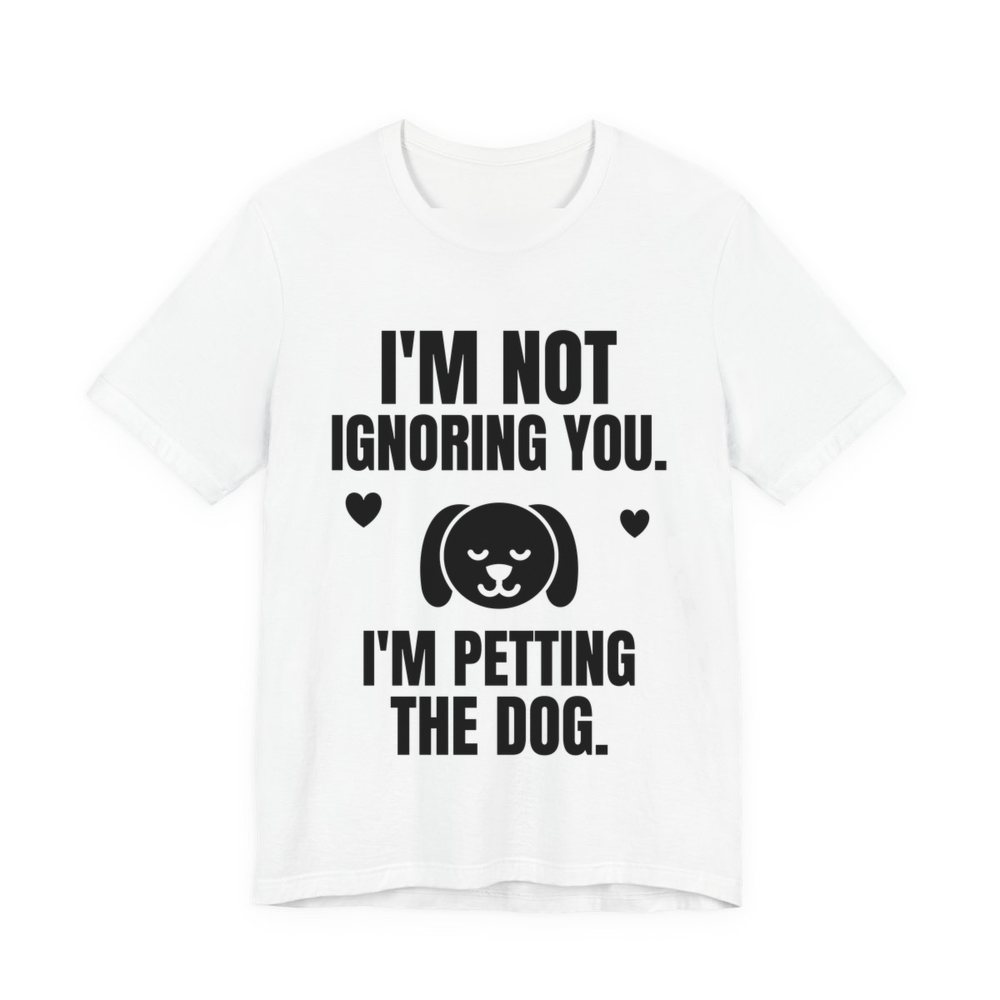 White t-shirt printed in dark ink with a content dog face with hearts and the words “I'm Not Ignoring You. I'm Petting the Dog.”