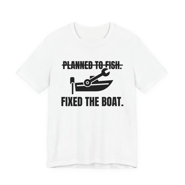 White t-shirt printed in dark ink with a boat and a wrench, with “Planned to Fish.” crossed out above “Fixed the Boat.”