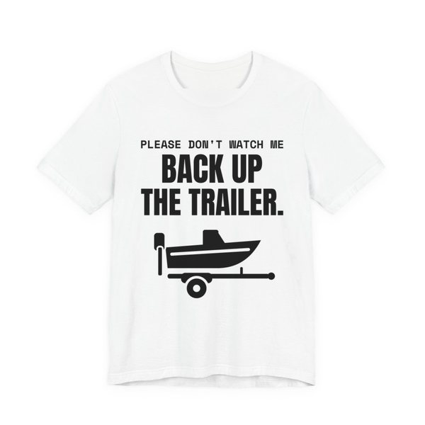 White t-shirt printed in dark ink with a boat on a trailer and the words “Please Don't Watch Me Back Up the Trailer.”