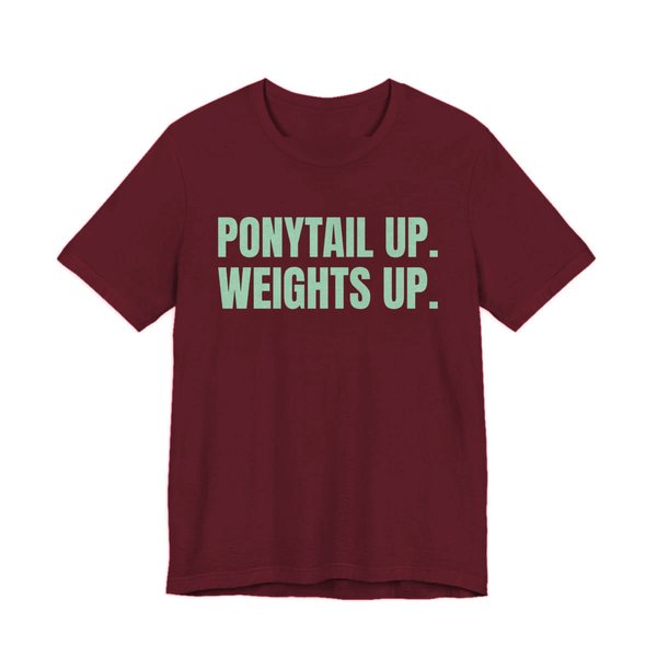 Maroon t-shirt printed in mint green ink with the words "Ponytail Up. Weights Up."