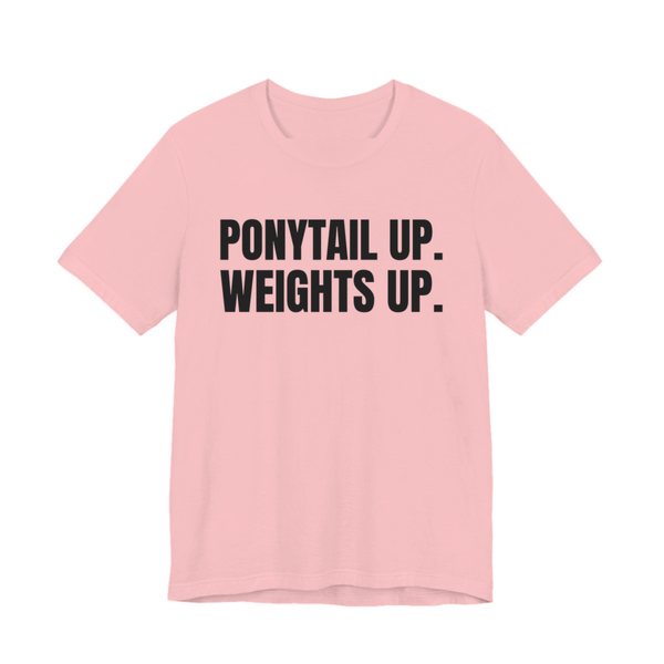 Pink t-shirt printed in dark ink with the words "Ponytail Up. Weights Up."