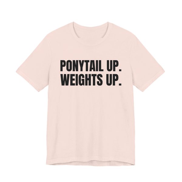 Soft Pink t-shirt printed in dark ink with the words "Ponytail Up. Weights Up."