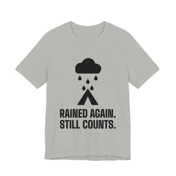 Athletic Heather t-shirt printed in dark ink with a rain cloud over a tent and the words “Rained Again. Still Counts.”