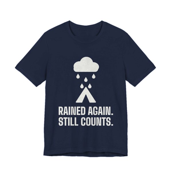 Navy t-shirt printed in off-white ink with a rain cloud over a tent and the words “Rained Again. Still Counts.”
