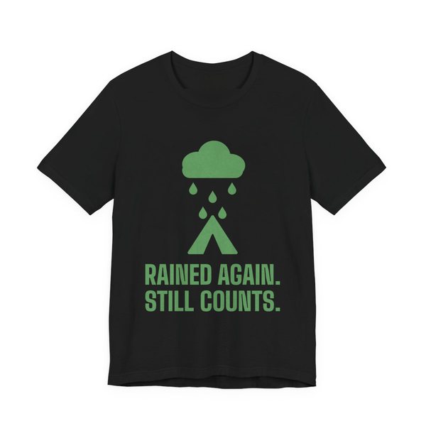 Black t-shirt printed in pine green ink with a rain cloud over a tent and the words “Rained Again. Still Counts.”