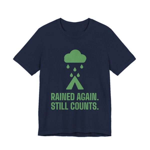 Navy t-shirt printed in pine green ink with a rain cloud over a tent and the words “Rained Again. Still Counts.”