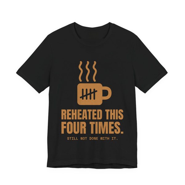 Black t-shirt printed in caramel ink with a mug with tally marks and the words “Reheated This Four Times.”