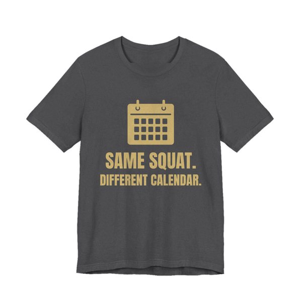 Dark Grey Heather t-shirt printed in champagne gold ink with a wall calendar and the words “Same Squat. Different Calendar.”