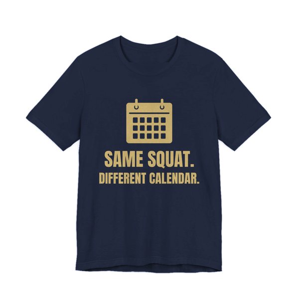 Navy t-shirt printed in champagne gold ink with a wall calendar and the words “Same Squat. Different Calendar.”