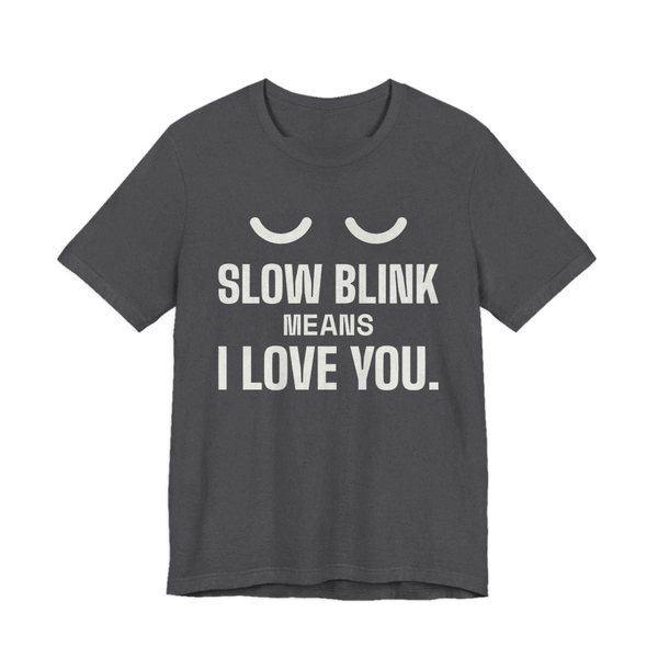 Dark Grey Heather t-shirt printed in off-white ink with a pair of closed cat eyes and the words “Slow Blink Means I Love You.”