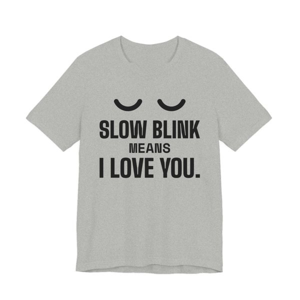 Athletic Heather t-shirt printed in dark ink with a pair of closed cat eyes and the words “Slow Blink Means I Love You.”