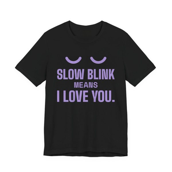 Black t-shirt printed in lavender ink with a pair of closed cat eyes and the words “Slow Blink Means I Love You.”