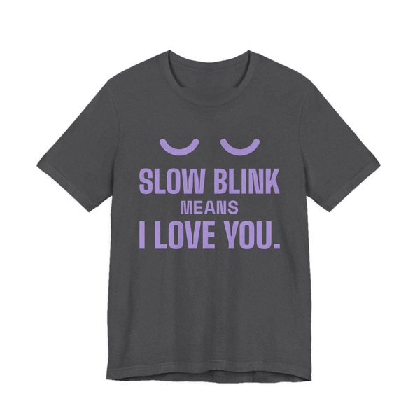 Dark Grey Heather t-shirt printed in lavender ink with a pair of closed cat eyes and the words “Slow Blink Means I Love You.”