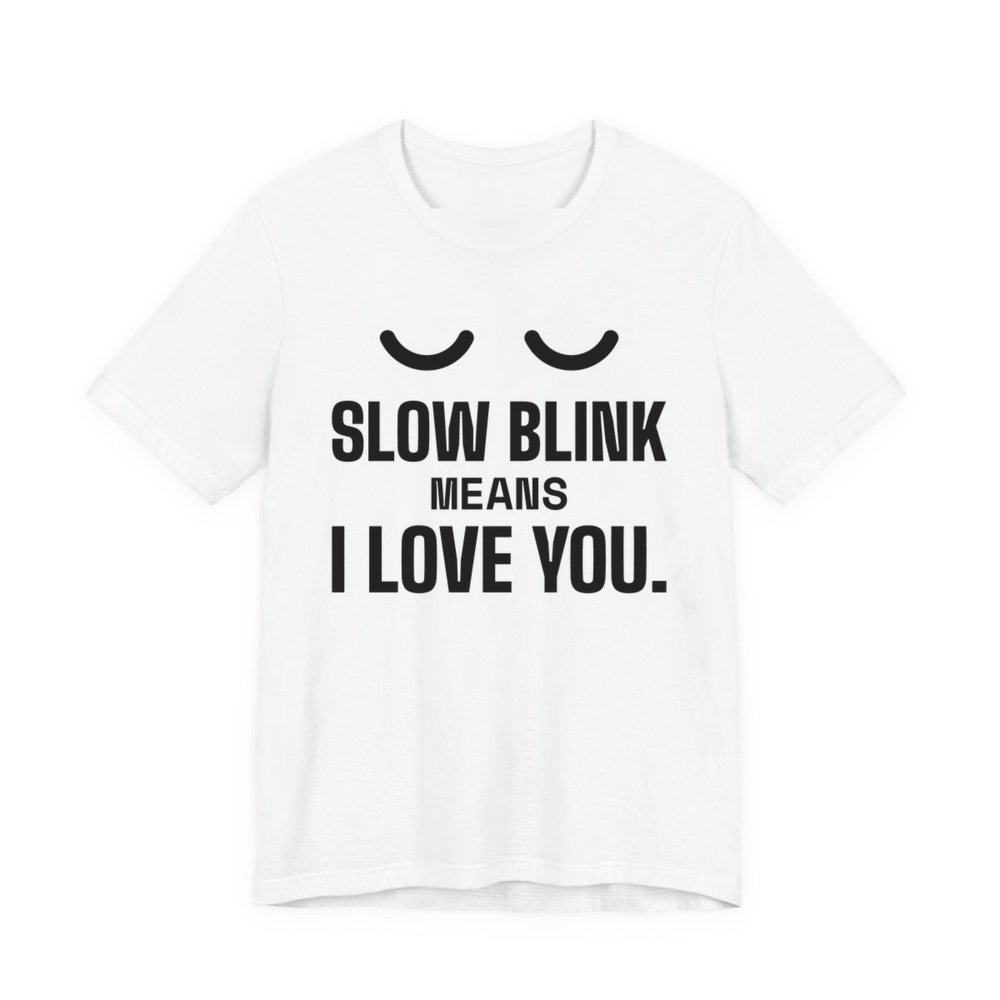 White t-shirt printed in dark ink with a pair of closed cat eyes and the words “Slow Blink Means I Love You.”