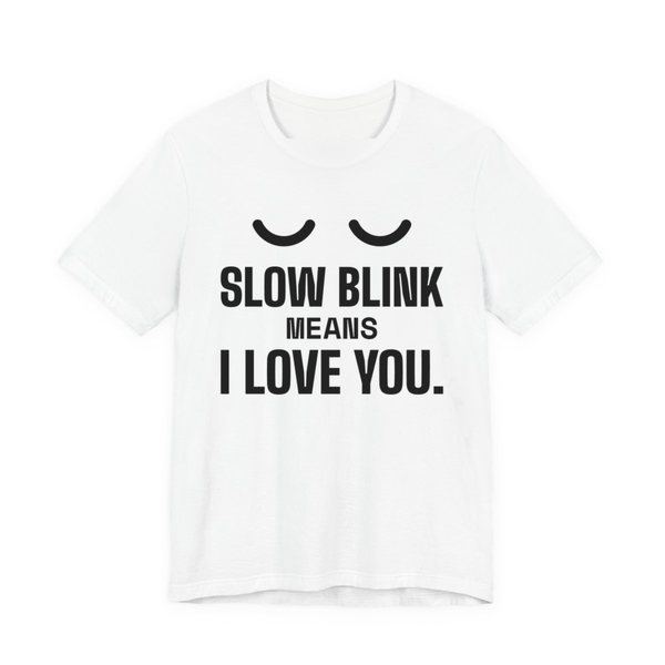 White t-shirt printed in dark ink with a pair of closed cat eyes and the words “Slow Blink Means I Love You.”