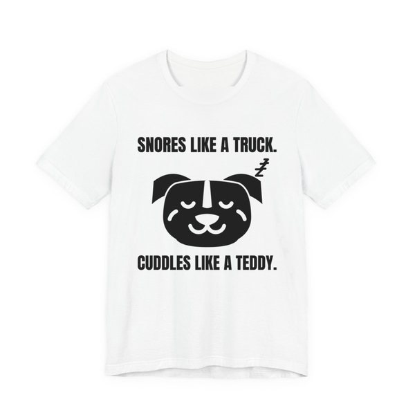 White t-shirt printed in dark ink with a sleeping pit bull face and the words “Snores Like a Truck. Cuddles Like a Teddy.”
