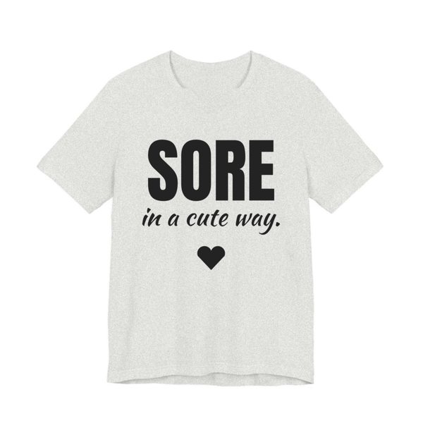 Ash t-shirt printed in dark ink with a heart and the words "Sore in a Cute Way."