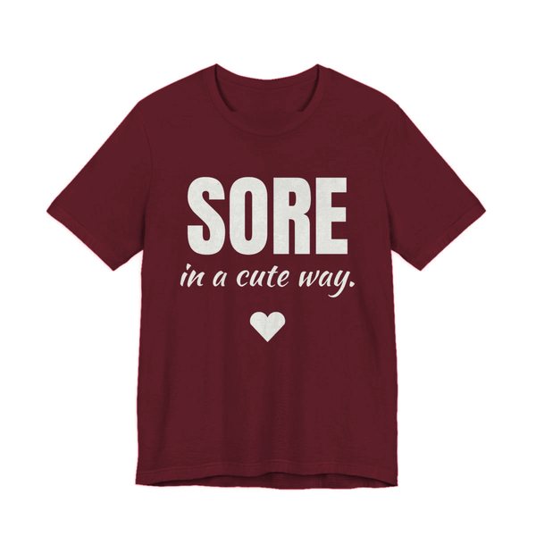 Maroon t-shirt printed in off-white ink with a heart and the words "Sore in a Cute Way."