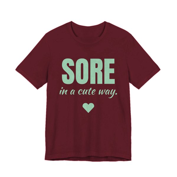 Maroon t-shirt printed in mint green ink with a heart and the words "Sore in a Cute Way."