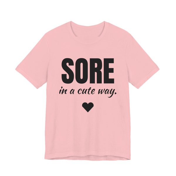 Pink t-shirt printed in dark ink with a heart and the words "Sore in a Cute Way."
