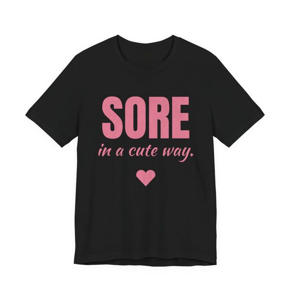 Black t-shirt printed in rose pink ink with a heart and the words "Sore in a Cute Way."