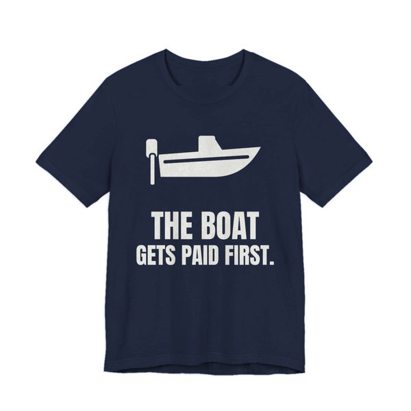 Navy t-shirt printed in off-white ink with a boat with an outboard motor and the words “The Boat Gets Paid First.”