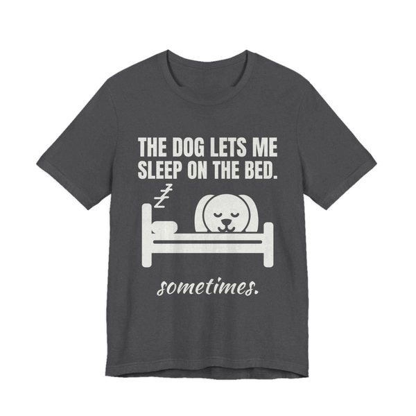 Dark Grey Heather t-shirt printed in off-white ink with a dog asleep in a bed and the words “The Dog Lets Me Sleep on the Bed. Sometimes.”