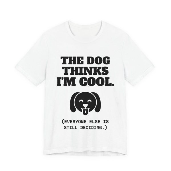White t-shirt printed in dark ink with a happy dog face and the words “The Dog Thinks I'm Cool. (Everyone else is still deciding.)”