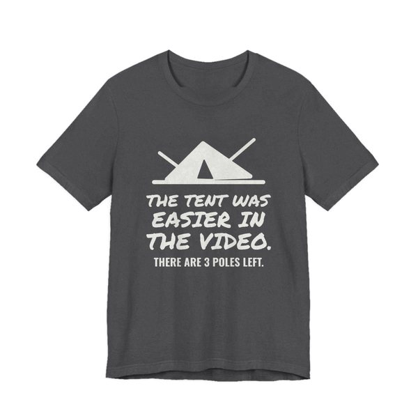 Dark Grey Heather t-shirt printed in off-white ink with a pitched tent with spare poles and the words “The Tent Was Easier in the Video. There are 3 poles left.”
