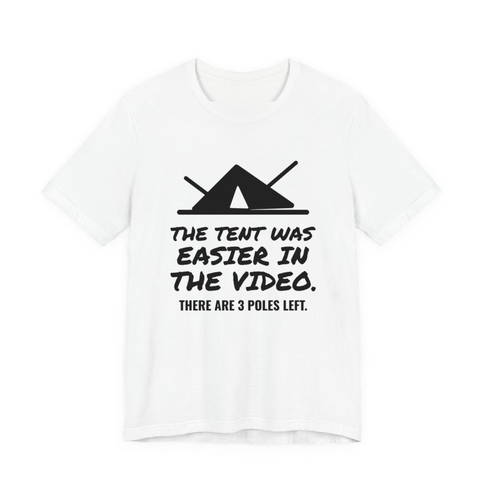 White t-shirt printed in dark ink with a pitched tent with spare poles and the words “The Tent Was Easier in the Video. There are 3 poles left.”