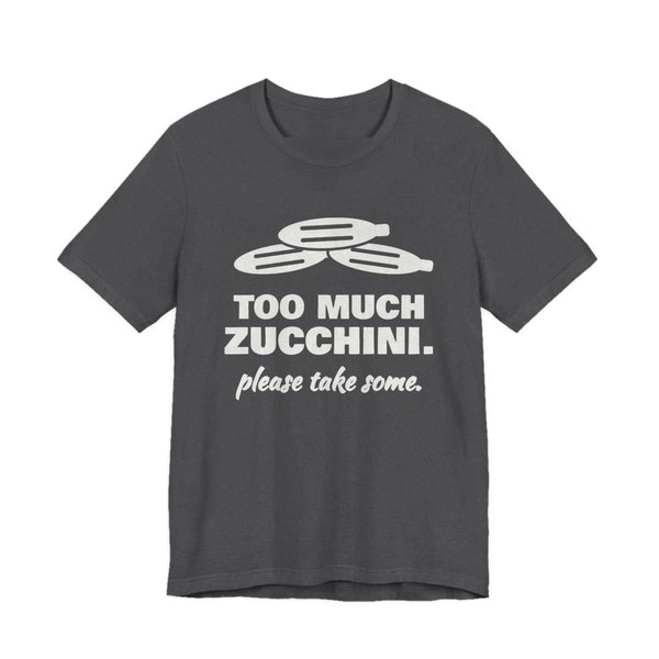 Dark Grey Heather t-shirt printed in off-white ink with a pile of zucchini and the words “Too Much Zucchini. Please Take Some.”