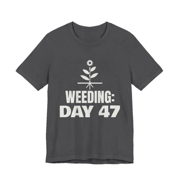 Dark Grey Heather t-shirt printed in off-white ink with a flowering weed with its roots and the words “Weeding: Day 47”