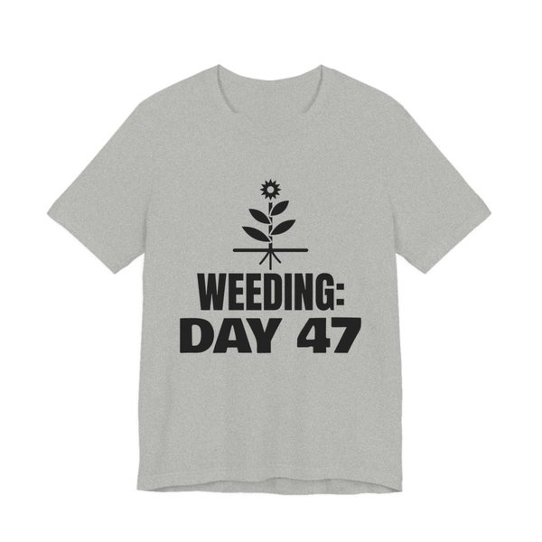Athletic Heather t-shirt printed in dark ink with a flowering weed with its roots and the words “Weeding: Day 47”