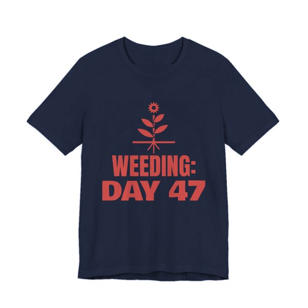 Navy t-shirt printed in tomato red ink with a flowering weed with its roots and the words “Weeding: Day 47”