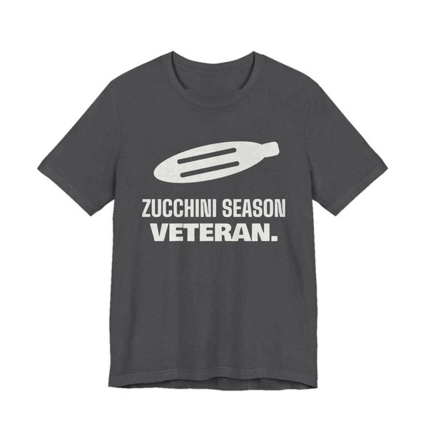 Dark Grey Heather t-shirt printed in off-white ink with a big zucchini and the words “Zucchini Season Veteran.”