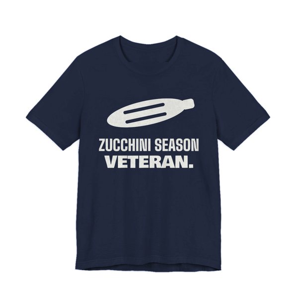 Navy t-shirt printed in off-white ink with a big zucchini and the words “Zucchini Season Veteran.”