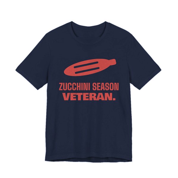 Navy t-shirt printed in tomato red ink with a big zucchini and the words “Zucchini Season Veteran.”